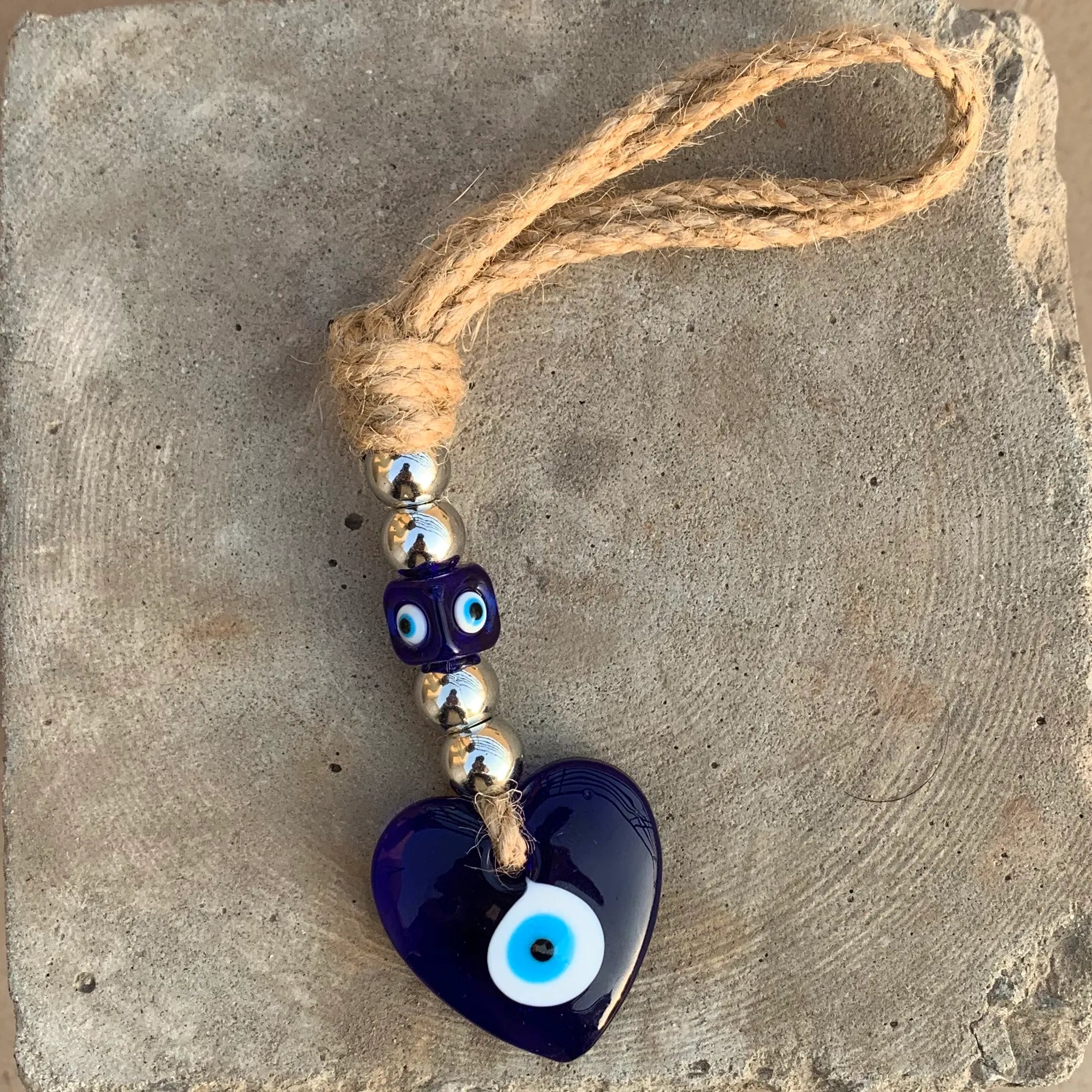 Blue heart-shaped pendant with a rope on a stone surface