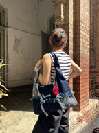 Person with a denim bag and striped shirt standing in front of a brick wall.