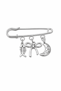 Silver safety pin with fish, bow, and moon charm on a white background
