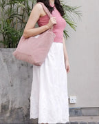 Woman holding a pink bag against a neutral background