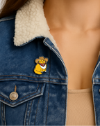 Person wearing a blue denim jacket with a white fur collar and a cartoon character pin.